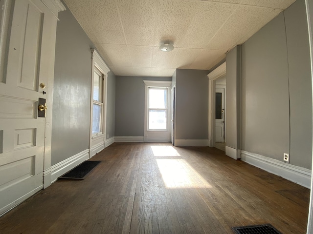 interior space featuring visible vents, dark wood-style flooring, and baseboards