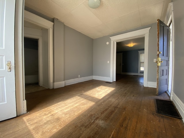 empty room featuring baseboards, wood-type flooring, and visible vents