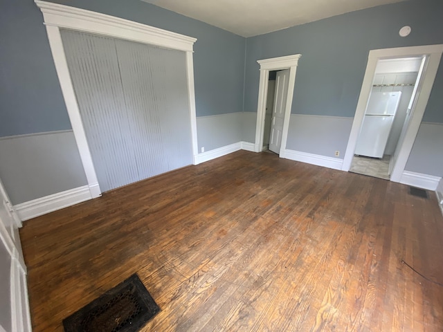 unfurnished bedroom featuring freestanding refrigerator and wood finished floors