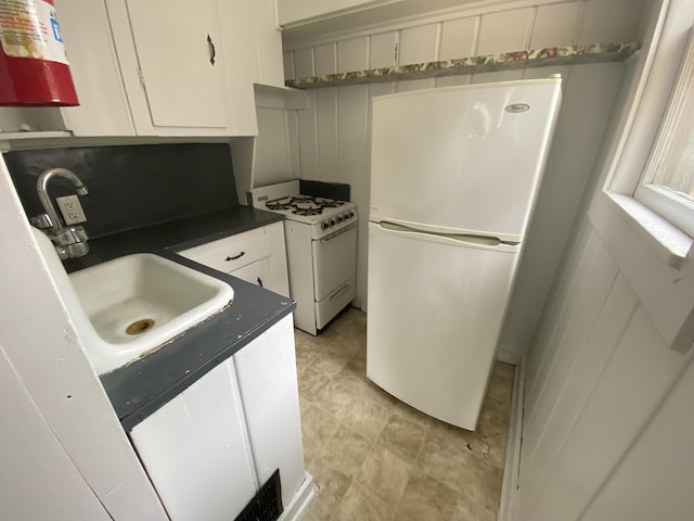 kitchen featuring white appliances, white cabinetry, a sink, and dark countertops