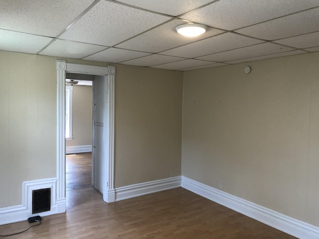 unfurnished room featuring visible vents, baseboards, a drop ceiling, and wood finished floors