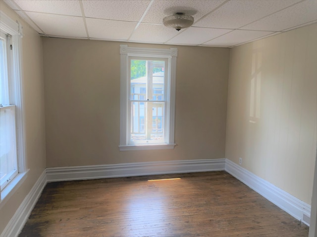 empty room with a paneled ceiling, wood finished floors, and baseboards