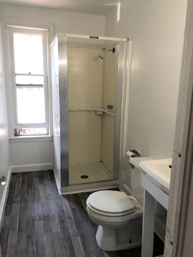 full bathroom featuring toilet, a stall shower, wood finished floors, and baseboards
