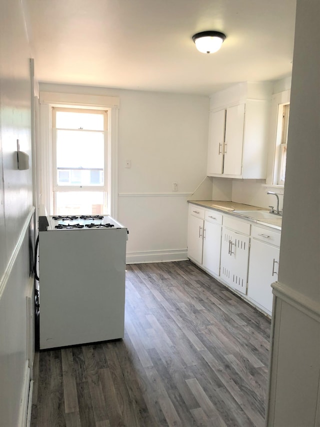kitchen with white cabinets, dark wood finished floors, a sink, and white gas range oven