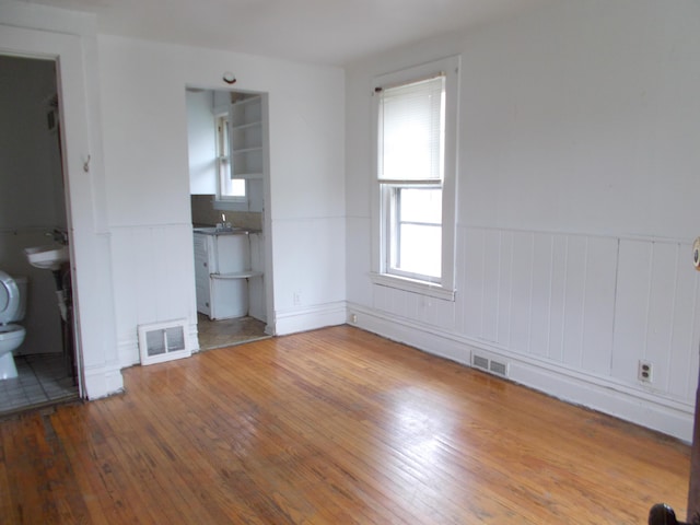 unfurnished bedroom with wainscoting, visible vents, and hardwood / wood-style flooring