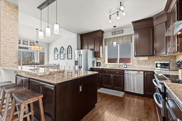 kitchen with dark wood-style floors, a sink, stainless steel appliances, dark brown cabinetry, and light stone counters
