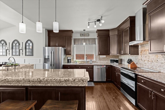 kitchen featuring a sink, dark brown cabinets, appliances with stainless steel finishes, and wall chimney range hood