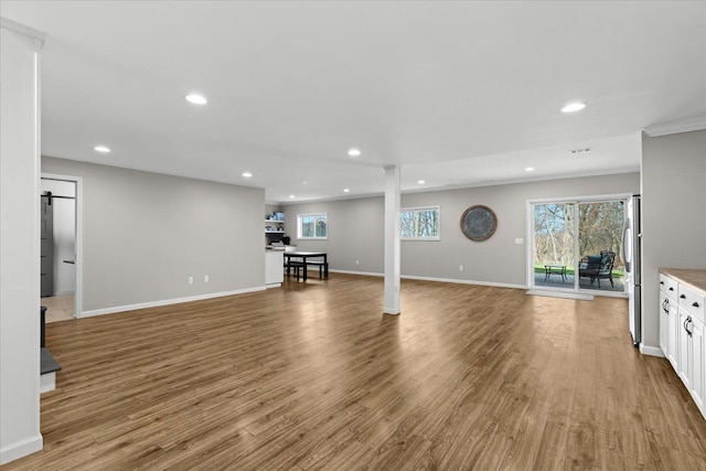unfurnished living room with recessed lighting, wood finished floors, and baseboards