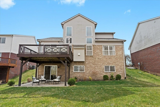 rear view of property featuring a patio, a deck, a lawn, and brick siding