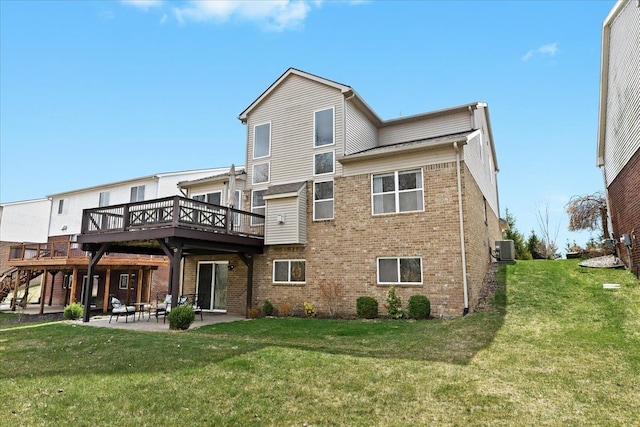 back of house with brick siding, a deck, a lawn, and a patio area