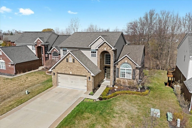traditional-style home featuring concrete driveway, roof with shingles, a front yard, and brick siding