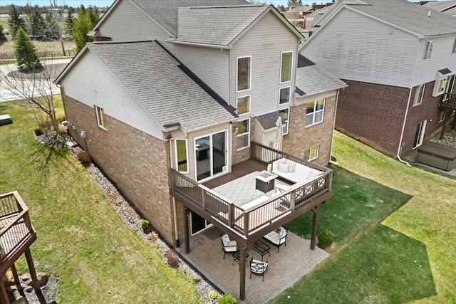 rear view of house with a deck, brick siding, a patio area, and a lawn