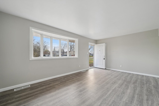 spare room with visible vents, baseboards, and wood finished floors