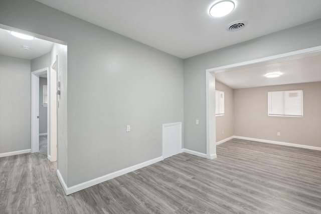 spare room featuring wood finished floors, baseboards, and visible vents