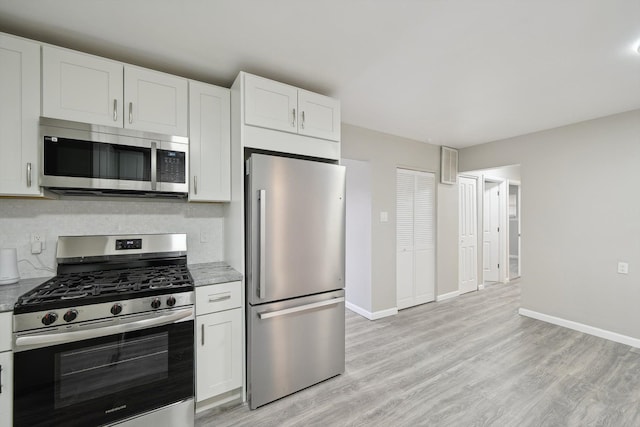 kitchen featuring light wood-style flooring, white cabinets, stainless steel appliances, baseboards, and backsplash