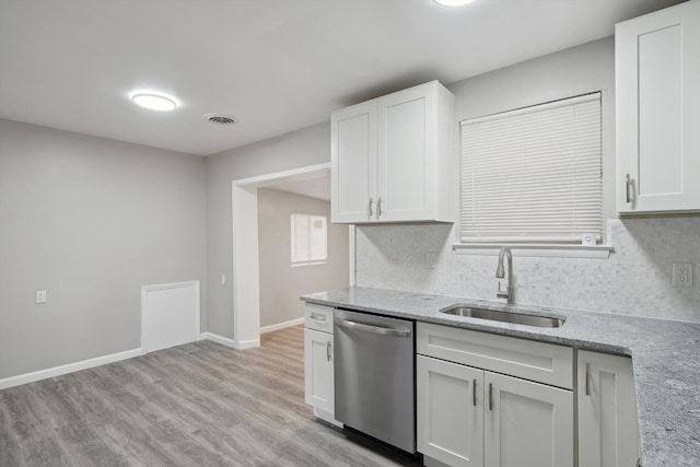 kitchen with baseboards, white cabinetry, light stone countertops, stainless steel dishwasher, and a sink