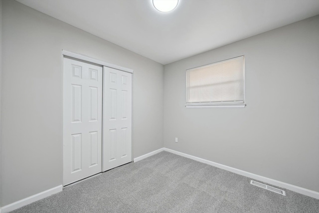 unfurnished bedroom featuring a closet, carpet flooring, visible vents, and baseboards