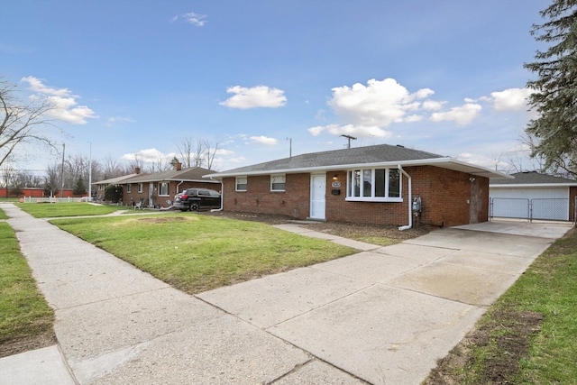 view of front facade featuring concrete driveway, a front yard, brick siding, an outbuilding, and a garage