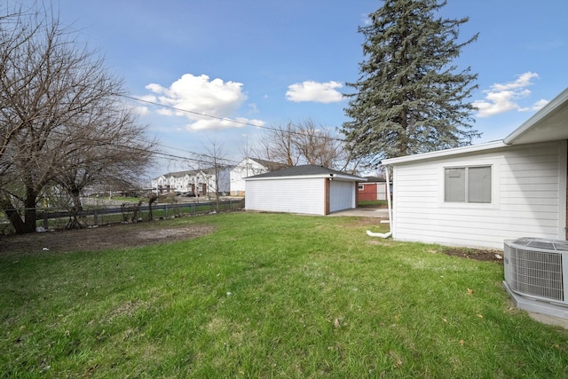 view of yard featuring central AC unit, a detached garage, fence, and an outbuilding