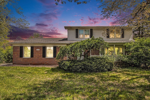 view of front of property featuring a lawn and brick siding