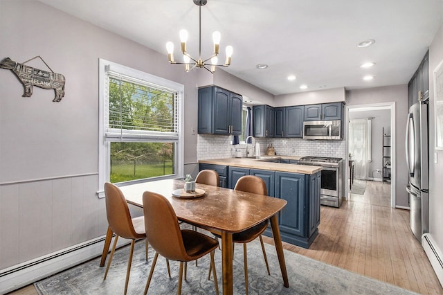 dining space with a baseboard heating unit, a chandelier, light wood-style floors, recessed lighting, and wainscoting