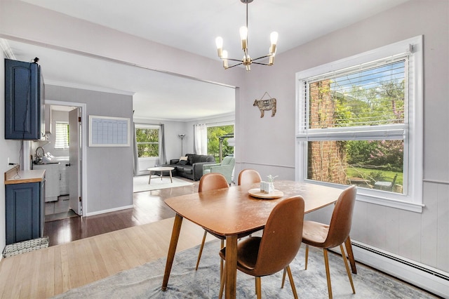 dining area with baseboard heating, a chandelier, wood finished floors, and baseboards