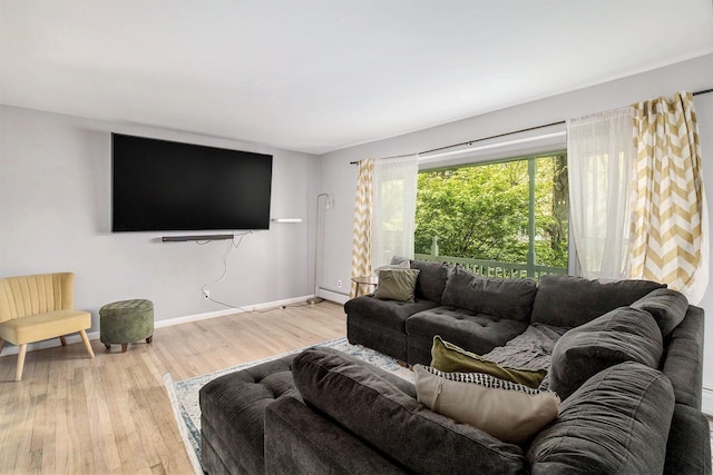 living area with wood finished floors, a baseboard heating unit, and baseboards
