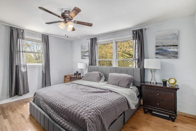 bedroom with light wood finished floors, a ceiling fan, and baseboards