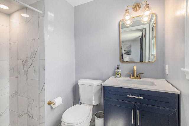 bathroom featuring toilet, vanity, and a tile shower