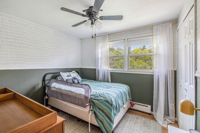 bedroom featuring baseboard heating, a ceiling fan, and wood finished floors