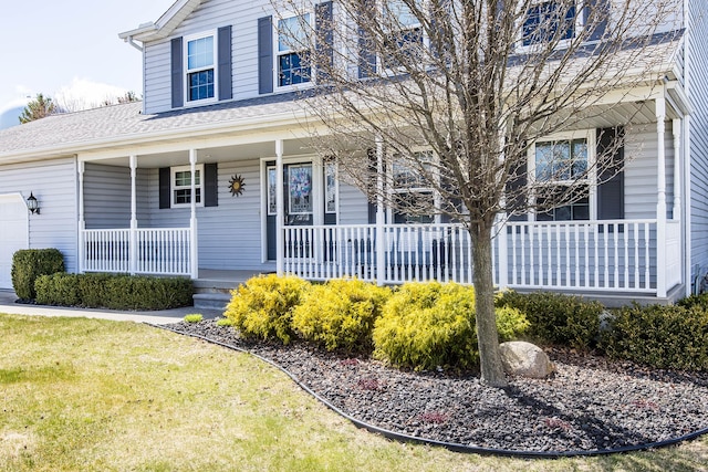 view of front of home featuring a porch, an attached garage, roof with shingles, and a front yard