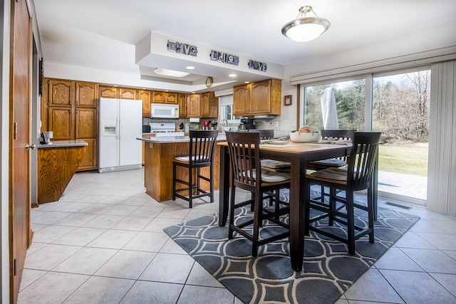 dining area featuring a tray ceiling, visible vents, and light tile patterned flooring