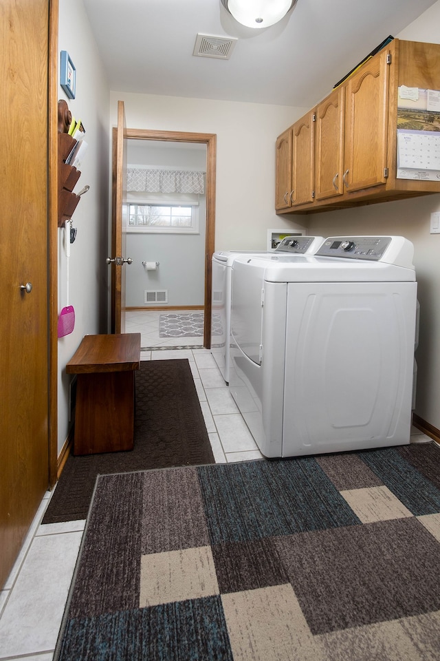 clothes washing area with cabinet space, washing machine and dryer, and visible vents