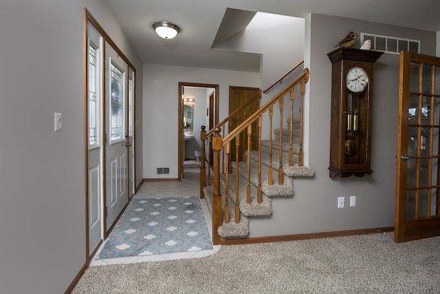 carpeted foyer featuring visible vents, baseboards, tile patterned flooring, and stairs