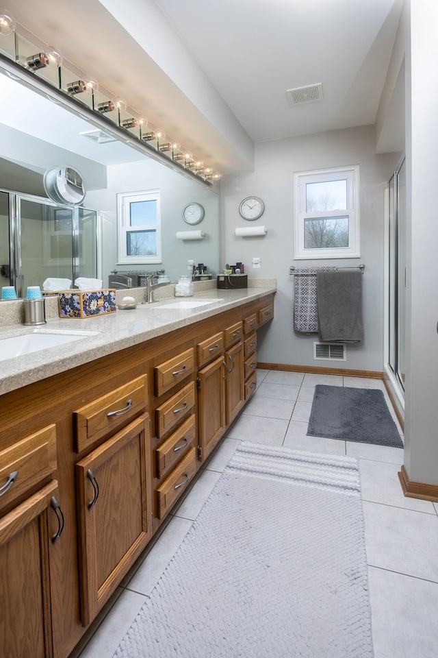 bathroom featuring visible vents, tile patterned flooring, a stall shower, and a sink