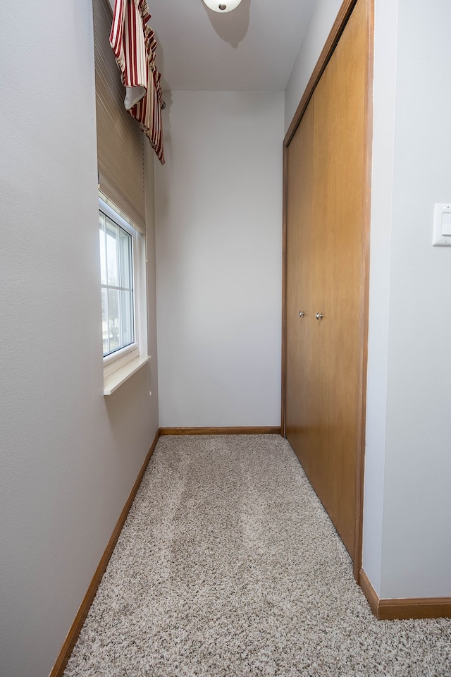 hallway with baseboards and carpet flooring