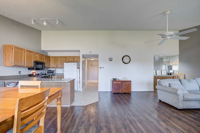 kitchen featuring black microwave, freestanding refrigerator, high vaulted ceiling, and open floor plan