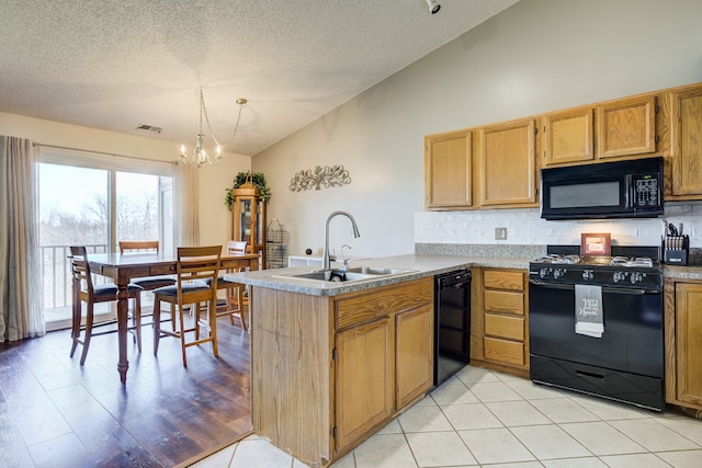 kitchen featuring lofted ceiling, an inviting chandelier, a sink, black appliances, and a peninsula