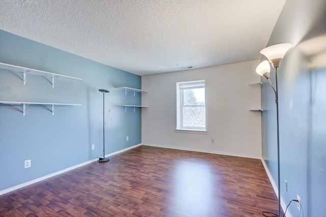 unfurnished living room with baseboards, visible vents, wood finished floors, and a textured ceiling