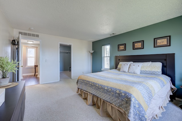 bedroom featuring light colored carpet, multiple windows, a textured ceiling, and visible vents