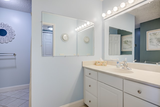 bathroom featuring baseboards, tile patterned floors, vanity, and a textured ceiling