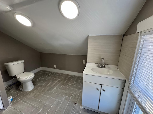 bathroom featuring lofted ceiling, vanity, toilet, and baseboards