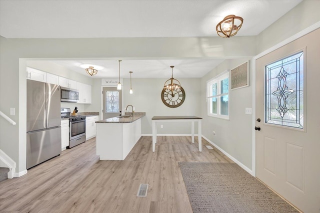 4965 Crestview Dr, Clarkston, MI 48348 - kitchen featuring appliances with stainless steel finishes, white cabinets, a peninsula, light wood-style flooring, and a chandelier