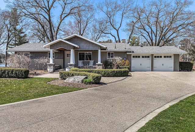 view of front facade with a chimney, concrete driveway, covered porch, a garage, and a front yard