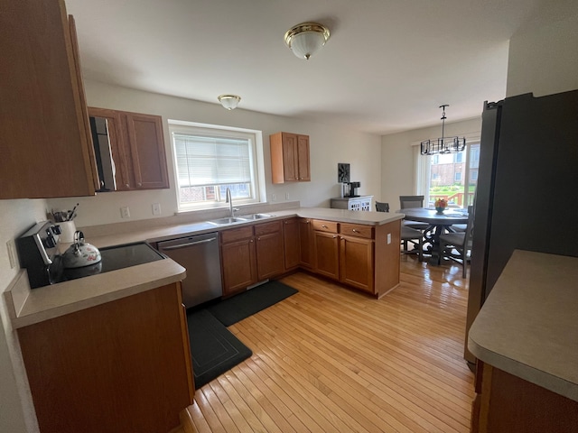 6181 Warwick Dr, Commerce Twp, MI 48382 - kitchen featuring appliances with stainless steel finishes, a sink, a peninsula, light wood-style floors, and a chandelier