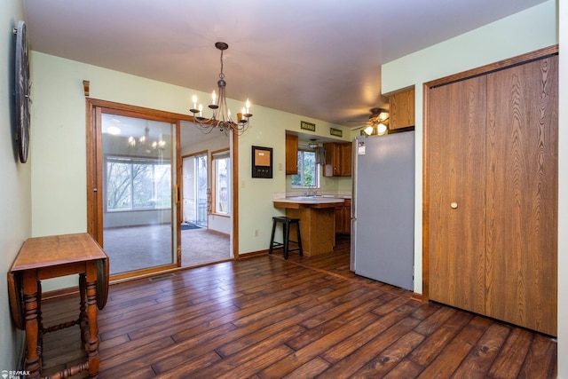 6051 Homestead Pl, Grand Blanc, MI 48439 - kitchen featuring a breakfast bar, a peninsula, dark wood-style floors, light countertops, and freestanding refrigerator