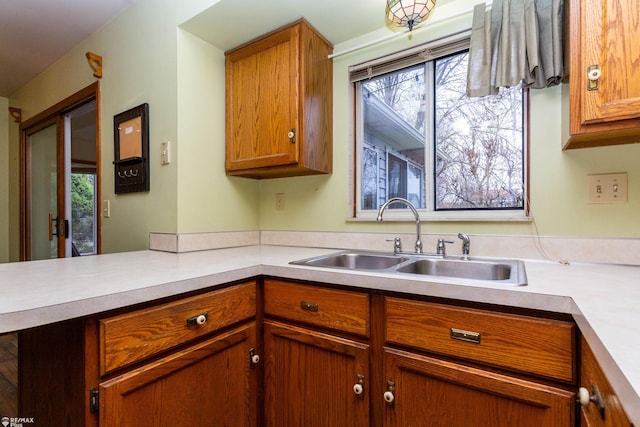 6051 Homestead Pl, Grand Blanc, MI 48439 - kitchen with brown cabinetry, light countertops, a sink, and a healthy amount of sunlight