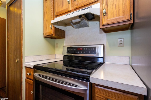 6051 Homestead Pl, Grand Blanc, MI 48439 - kitchen featuring stainless steel range with electric stovetop, under cabinet range hood, brown cabinets, and light countertops