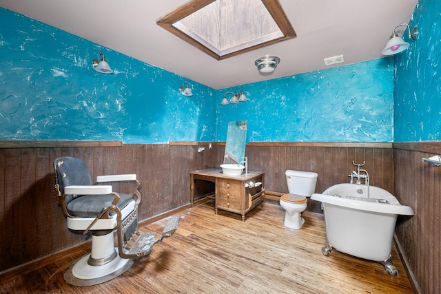 70700 Ironwood Dr, Niles, MI 49120 - full bathroom featuring a freestanding bath, toilet, wainscoting, wallpapered walls, and a skylight