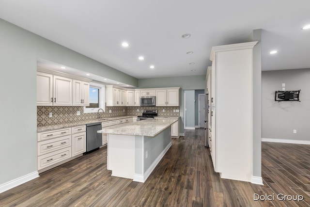 kitchen featuring tasteful backsplash, white cabinets, appliances with stainless steel finishes, a sink, and dark wood-style floors